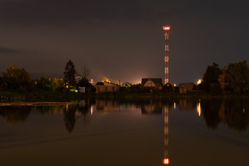 Fototapeta na wymiar Night city landscape with a pond and a cell tower