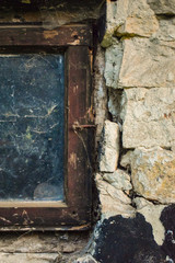 old wooden window with dirty glass and cobweb of old stone house with dark plaster