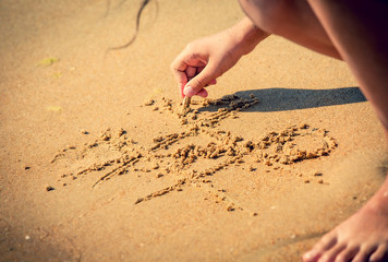 tic tac toe game or X O game write on sand. Fun and games on the sandy beach. Children's hand draws a shell on the sand