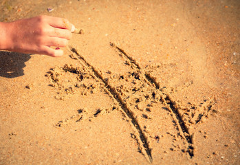 tic tac toe game or X O game write on sand. Fun and games on the sandy beach. Children's hand draws a shell on the sand