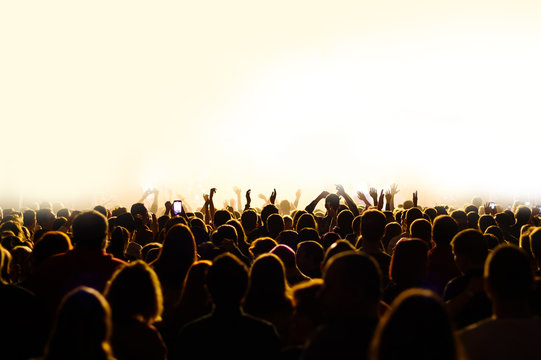 crowd with raised hands at a concert of a music festival. Silhouettes of people in front of a stage with an artist. night disco