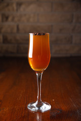 Glass of alcoholic drink with coffee grains on a wooden old table