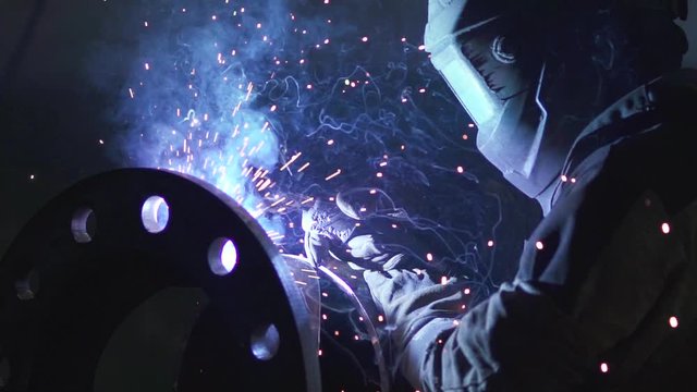 Metalworks craftsmanship. Professional Industrial worker welder welds steel parts at his workshop