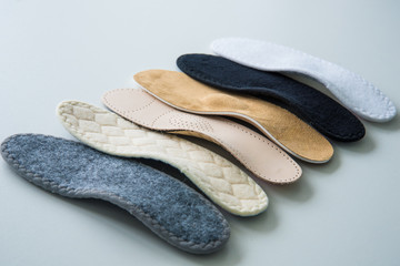 Studio photo of orthopedic insoles. A variety of orthopedic insoles are laid out in a row....