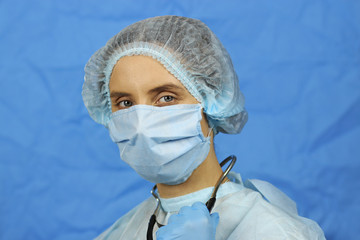 Female doctor in a dressing gown, cap and medical mask with a stethoscope around his neck