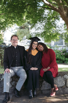 Parents and robe wearing daughter in the yard.