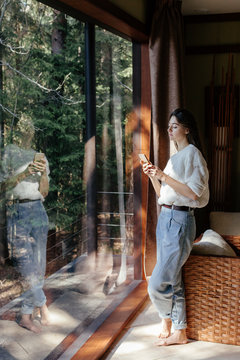 Fototapeta Woman standing near panoramic window