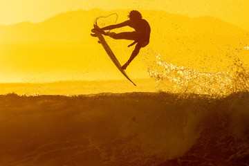 silhouette of a surfer doing an air at sunrise
