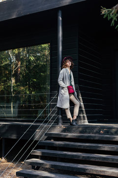 Stylish woman standing near modern black cottage