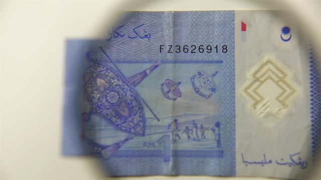 One Malaysian ringgit and magnifying glass. View a paper bill through a magnifying glass. reverse.