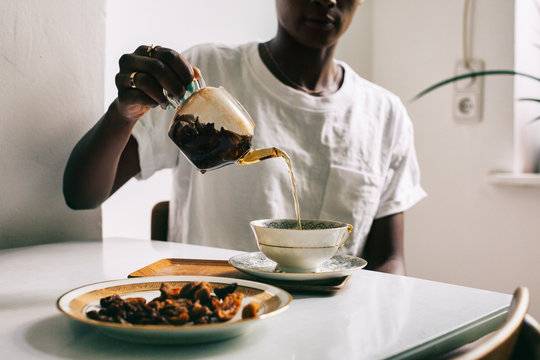 Anonymous Black Woman Pouring Tea Into Cup