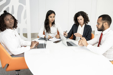 Fototapeta premium Professional business team with laptops and papers. Group of professional multiethnic business colleagues working with computers and documents in office. Business concept
