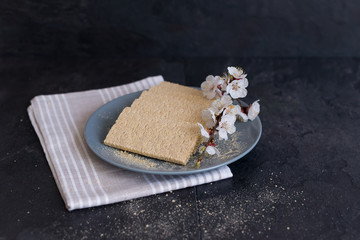 Crispbread with fruit tree flowers on a gray plate on a black background with a light cotton cloth....