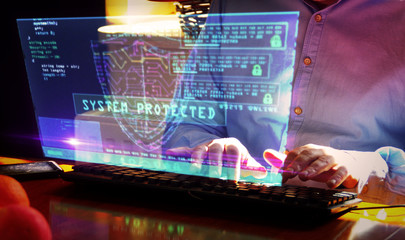 Man typing on keyboard with security shield symbol hologram screen