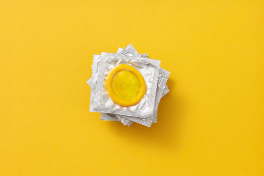 Stack of condom's packs on an yellow.