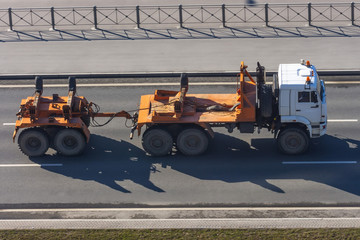 An empty timber truck with a trailer rides on a highway in the city.