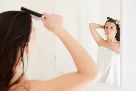 Woman brushing long wet hair in bathroom