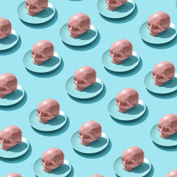 Plates with pink skulls as a pattern on a blue background with reflection of shadows.