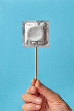 Woman hand with condom on a stick.