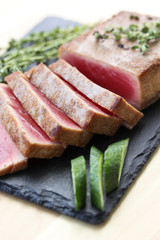 Fried tuna with thyme and fresh cucumber on a black board on a light background. Seafood. Background image, copy space
