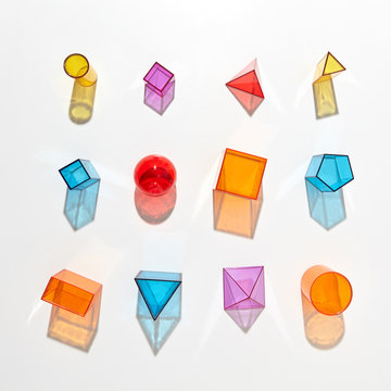 A set of diverse multicolored geometric shapes with reflection on a light background. Flat lay