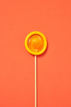 Yellow condom on a stick as a lollipop.