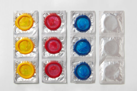 Strips from colored condoms on light grey.