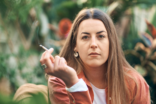 Woman In A Lush Garden Relaxing Smoking Cannabis