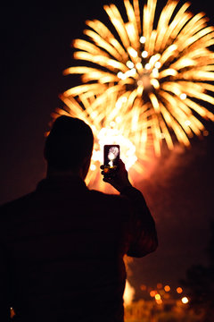 Man photographing fireworks using smartphone