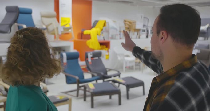 Young couple choosing chair in furniture store