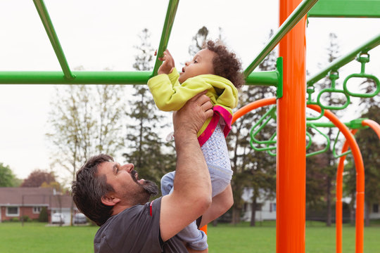 Pretty smiling toddler girl being lifted into the air by her smiling father