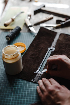Detail of a handmade process: man makes a product (bag) from leather.