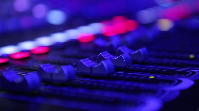 Electric machine on table for working of sound designer or club dj at party in nightclub in neon blue and violet lighting.Occupation for modern lifestyle, objects for listen at background. 