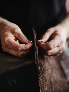 Detail of a handmade process: man makes a product (bag) from leather.