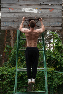 powerful street work-out of the crossfit athlete - doing pull-ups on a basketball ring