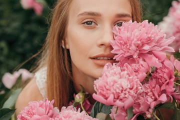 Pretty young woman posing in pink flowers