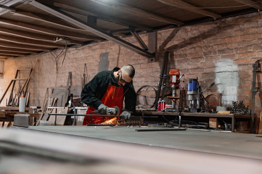 Metal worker in glasses cutting details