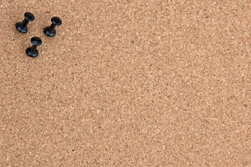 Three black tacks in cork board
