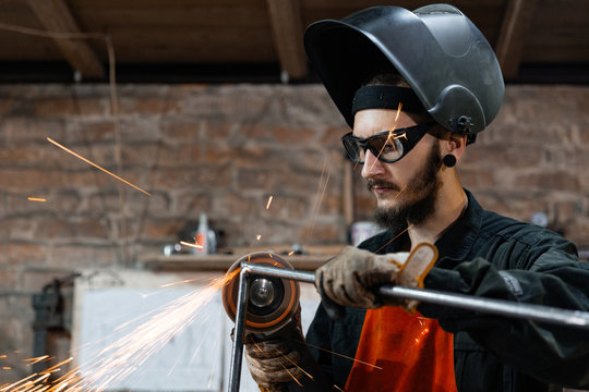Young metal worker grinding frame