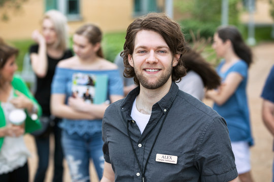 Tour: Smiling Tour Guide With Group Behind