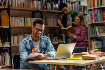 Young male student study in the library using laptop for researching online.