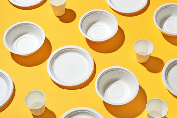 Eco friendly disposable dishes, cups, bowls on yellow background