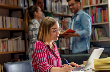 Young female student study in the library using laptop for researching online.