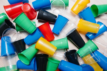 A large pile of multicolored plastic cups scattered on the floor. Pollution of the environment by human waste