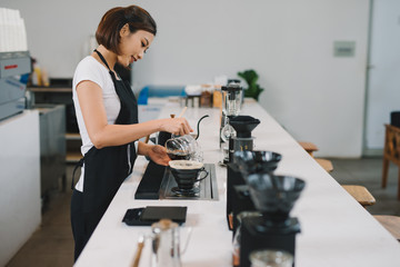 Young female starting her day on a new job as a barista. Working in a cafe.