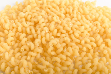 Heap of dried serpentelli traditional Italian pasta in a round bowl ready to be cooked, isolated on a white table, top view or flat lay of healthy food 

