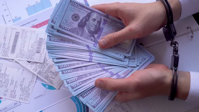 businessman in handcuffs counts the money transferred. concept of corruption and bribes