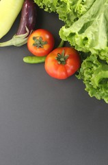 Vegitables on a black background (tomatos, escarole leaves, brinjal or egg plant, chillis, capcicum banana pepper closeup shot with copy space