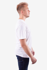 Caucasian man stands sideways to the camera and looks ahead. White background