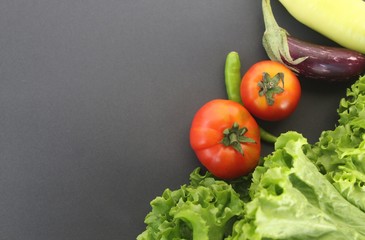 Vegitables on a black background (tomatos, escarole leaves, brinjal or egg plant, chillis, capcicum banana pepper closeup shot with copy space